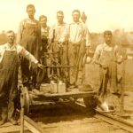 With the smoke stacks and kilns of the Medora Brick Plant in the background (right) this Sparksville Baltimore & Ohio Railroad section crew poses at the head of the brick plant spur. Supervisor at far left is believed to be Elmer Rudder who later (1914) was a supervisor at the plant. No date or names known for sure, but if you have information about this photo, please email info@medorabrickplant.org photo credit - the Jackson County, Indiana, Digital History Archive Project